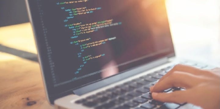 A person developint HTML on a laptop with the sun shining on it. 