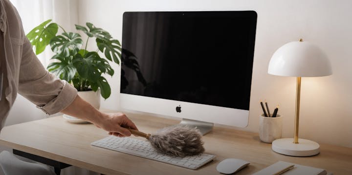 A person dusting a Mac computer